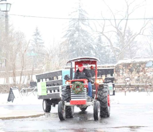 A festive tractor pulls a wagon through the snow during the Old Fashioned Christmas event at the Rochester Hills Museum.