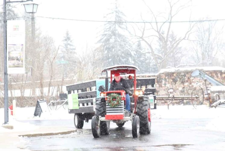 A festive tractor pulls a wagon through the snow during the Old Fashioned Christmas event at the Rochester Hills Museum.