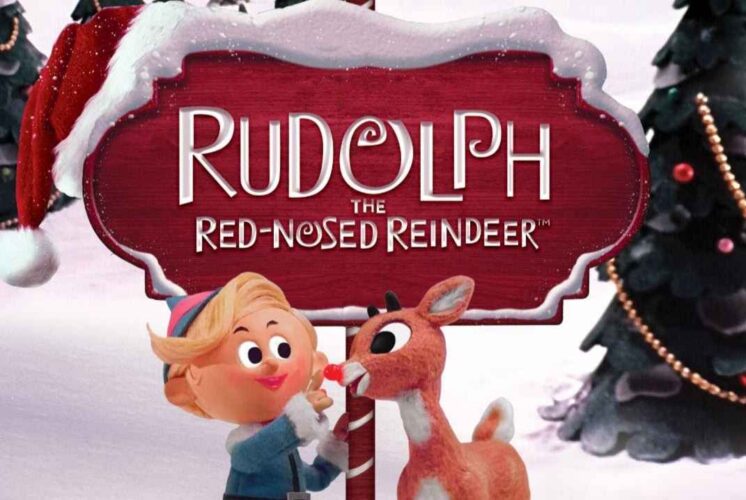 Rudolph the Red-Nosed Reindeer and Hermey the Elf stand by a snowy sign promoting the family holiday show at Trenton Village Theatre.