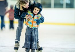 Family skating at Skate for a Cause Southfield Sports Arena as a child learns to skate with support during the community event