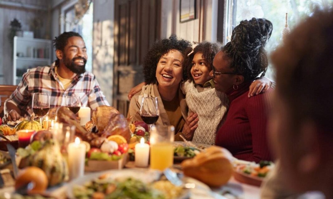 Family gathered at a Thanksgiving dinner table during a Detroit holiday break celebration with food candles and warm togetherness.