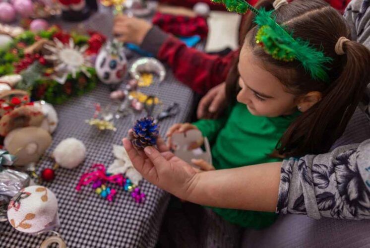 Child creating a holiday craft at Craft with a Cop Farmington Hills with colorful supplies and hands on guidance from an adult