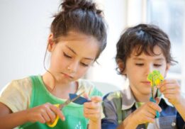 Children cut paper during a craft activity similar to the Create Workshops at Decked Out Detroit where kids can enjoy creative hands on projects