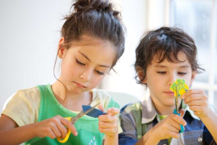 Children cut paper during a craft activity similar to the Create Workshops at Decked Out Detroit where kids can enjoy creative hands on projects
