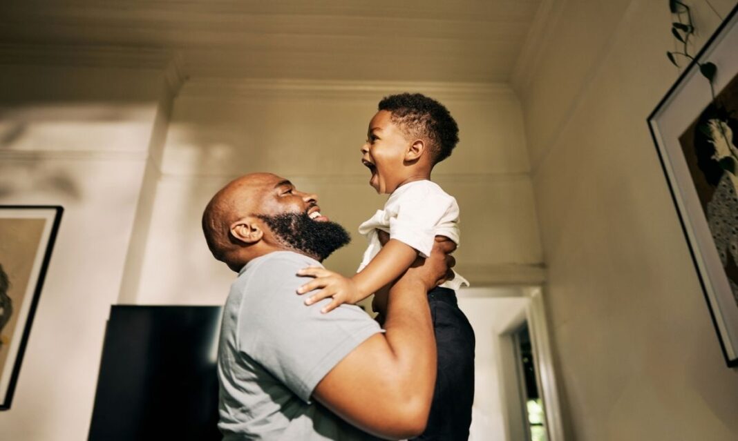 Detroit dad lifting his young son indoors, showing a playful father-son moment during winter activities for elementary kids.