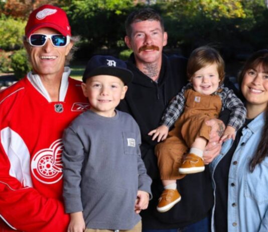 A Red Wings alumni player stands with a family at Big Boy Arena during the Detroit Red Wings Alumni Game supporting local families facing cancer