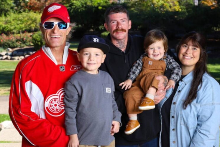 A Red Wings alumni player stands with a family at Big Boy Arena during the Detroit Red Wings Alumni Game supporting local families facing cancer