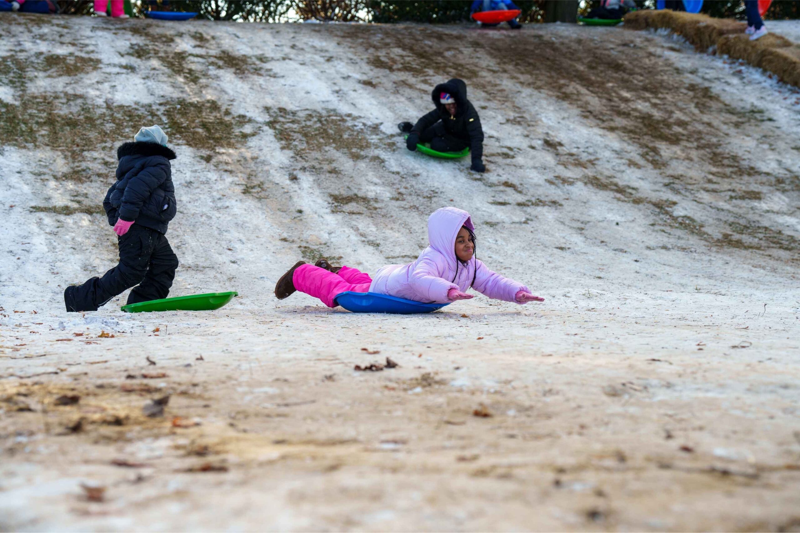 Children sled down a snowy hill during the Hyde Park Art Center MLK Day celebration featuring free outdoor fun for families