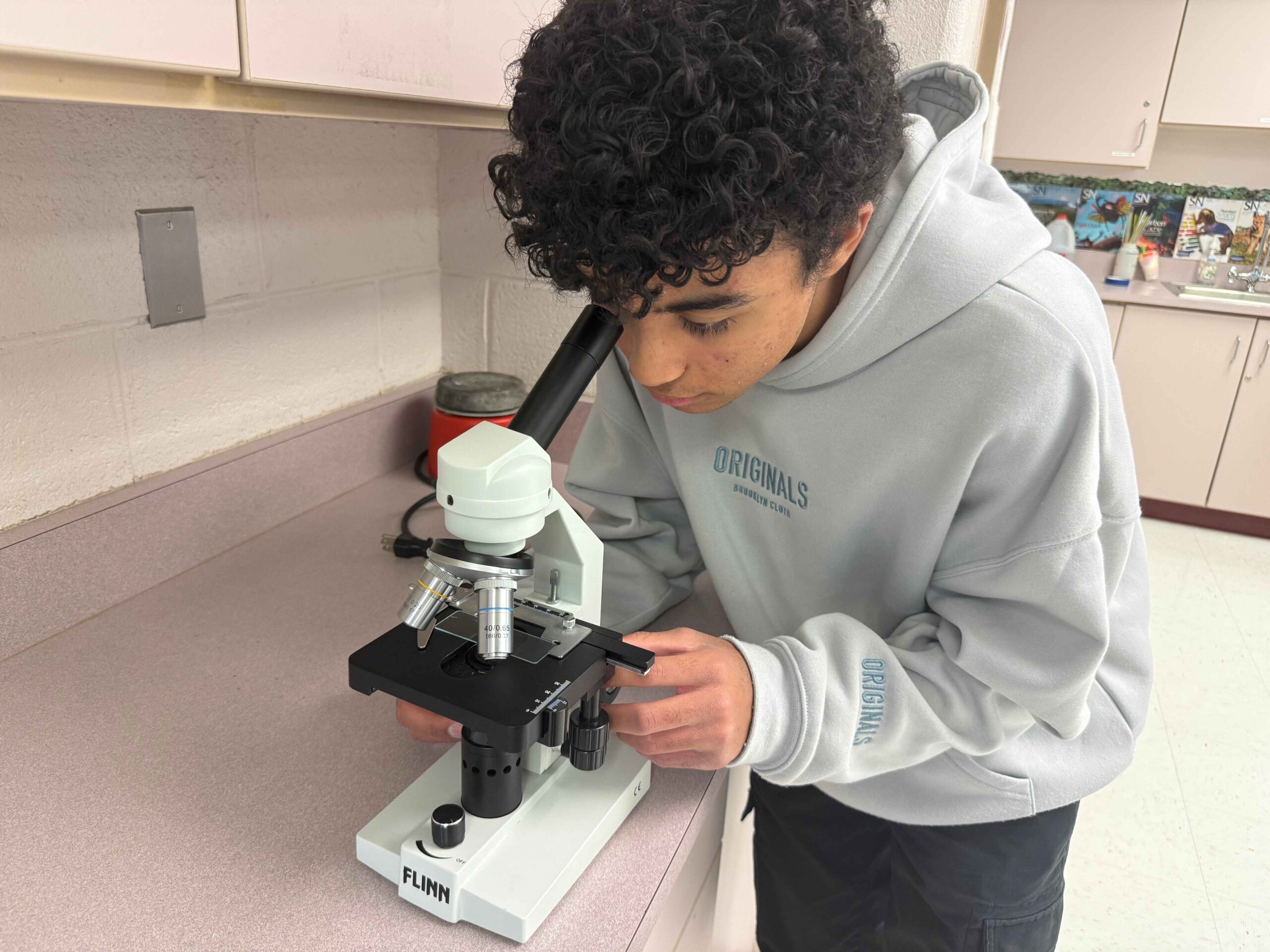 International Academy of Macomb student uses a microscope during hands-on science learning in an IB-focused high school classroom