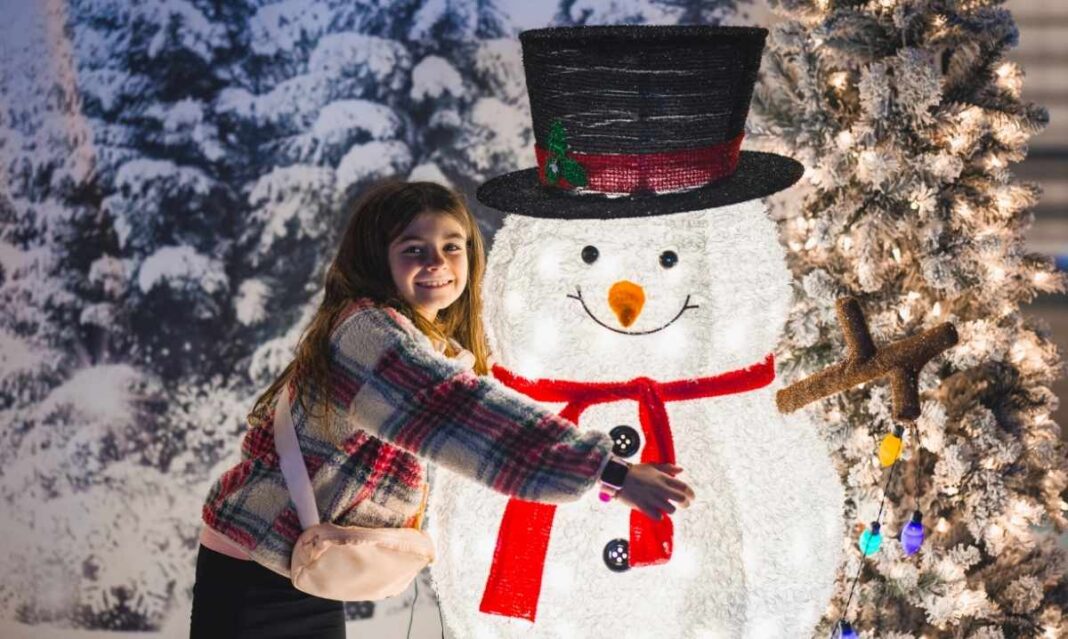A child poses with a glowing snowman during the Magic of Lights drive-through holiday show at Pine Knob Music Theatre in Clarkston Michigan.