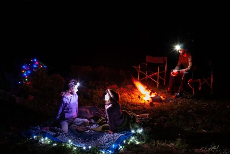 Night Light Hike Nankin Mills Interpretive Center showing families by a campfire with headlamps during a guided winter evening hike and storytelling outdoors