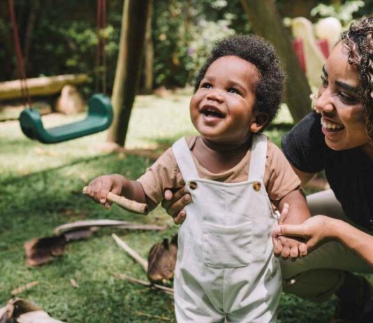 Rock Around the Hawk at The Hawk Community Center Toddler smiling with a caregiver outdoors for Rock Around the Hawk Farmington Hills as little ones enjoy playful music inspired activities