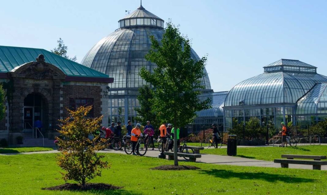 Visitors outside Belle Isle Aquarium in Detroit on a sunny day showing the historic glass conservatory families explore with kids