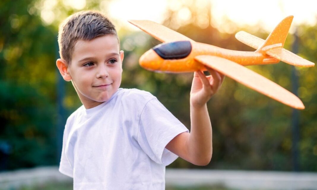Young child holding a toy airplane outdoors, representing a special interest that can support learning and social connection for children with autism
