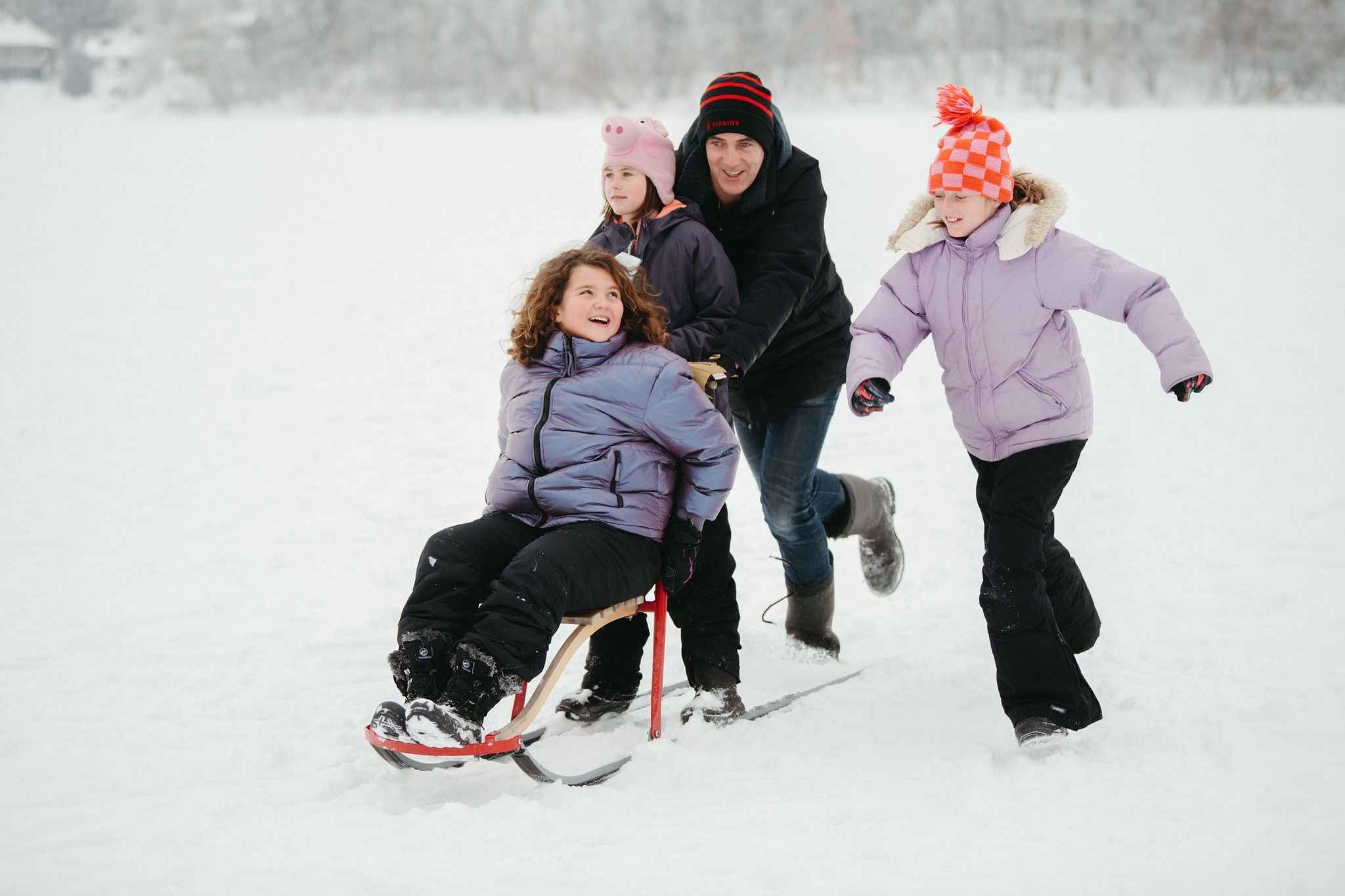 Family enjoying sledding during a Midwest winter getaway near Metro Detroit, kids playing in the snow on a cold winter day
