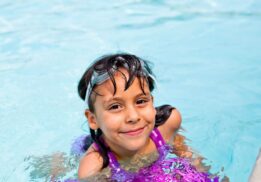 Smiling child enjoys Kiddie Swim at Troy Community Center during a shallow pool swim time designed for young kids ages 6 and under