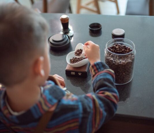 Child scoops coffee beans during Kids and Coffee at Dozer Coffee, a hands on activity teaching kids about coffee roasting and measuring beans