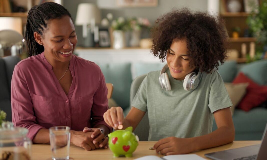 Mother and child at home saving money in a piggy bank for college, representing 529 planning and student loan awareness for metro Detroit families.