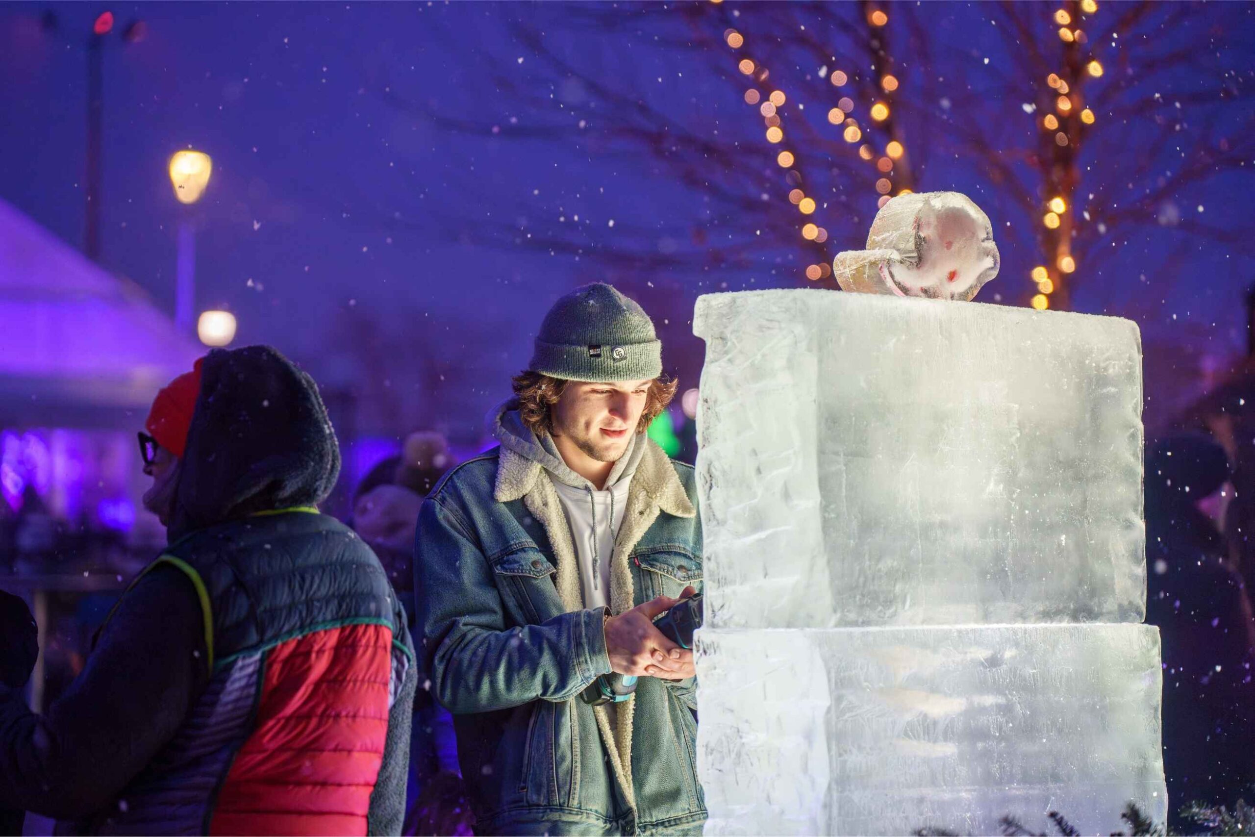 An ice artist carves a sculpture during Winter at Valade at Robert C Valade Park as families enjoy evening winter activities