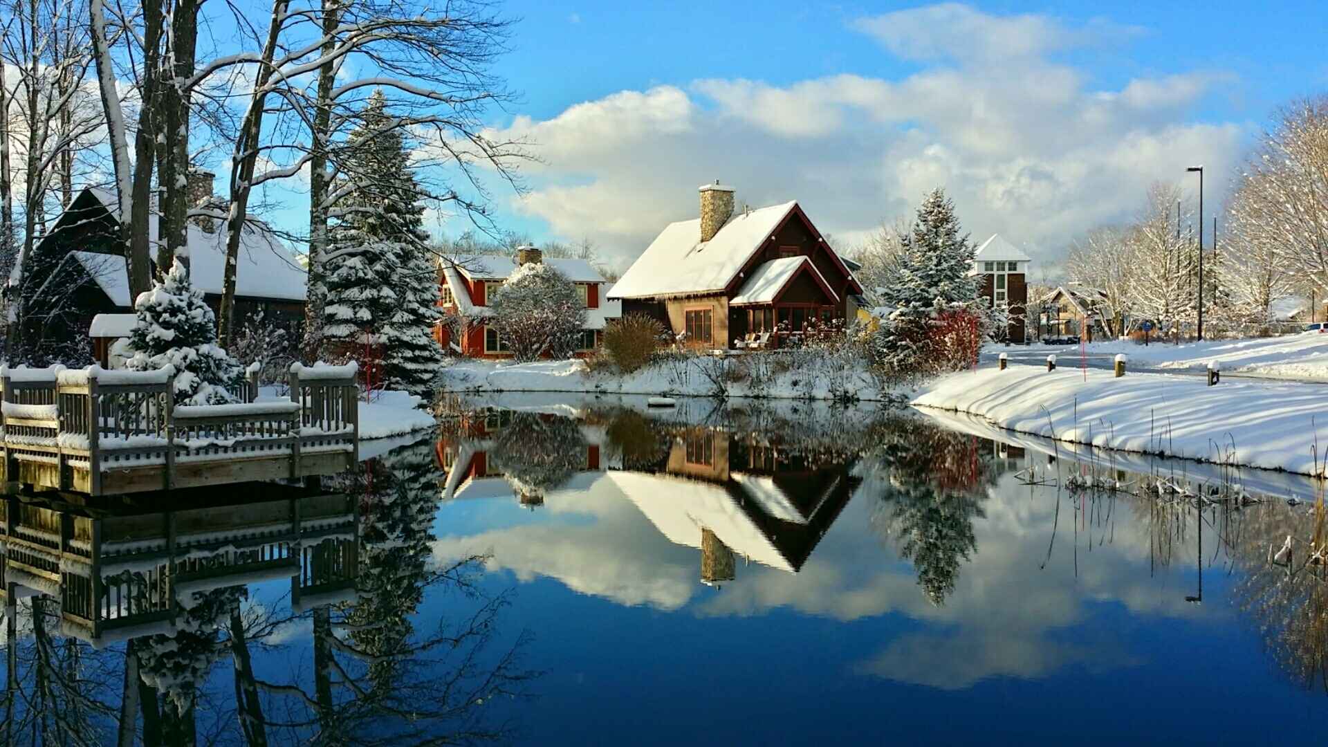 Snow covered homes and Crystal Mountain resort village reflected in a pond in Thompsonville, Michigan during winter.