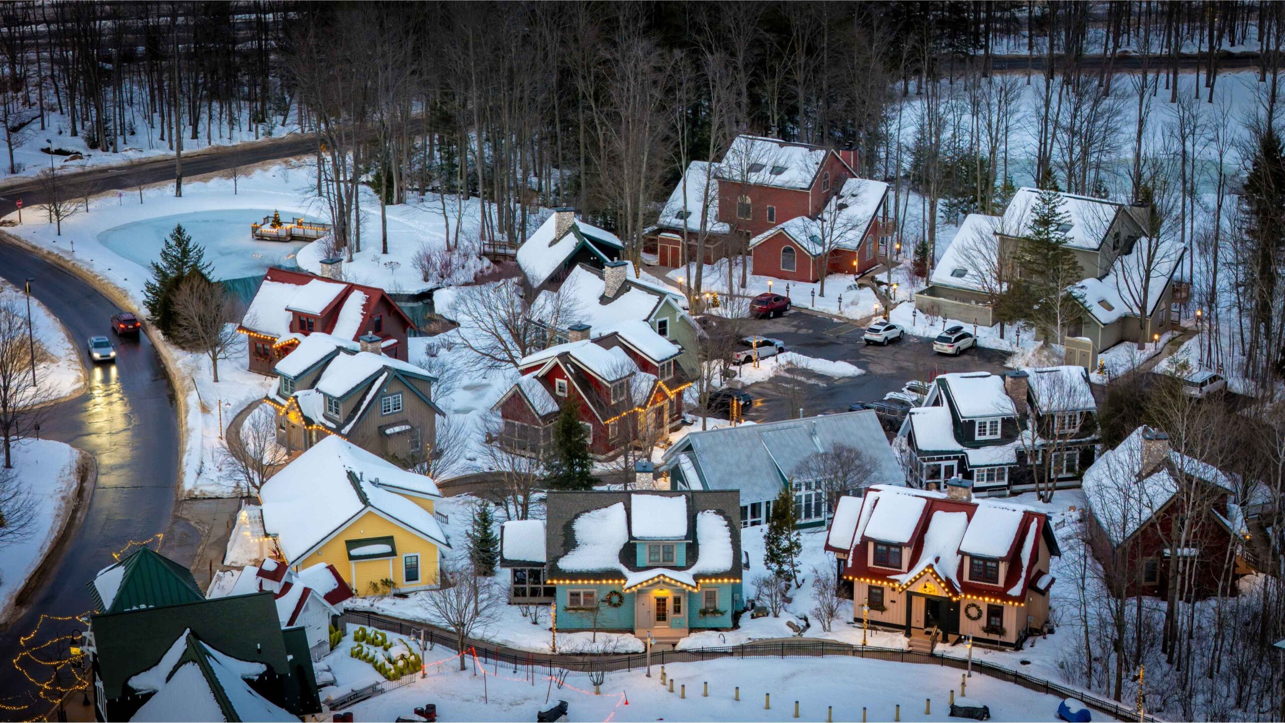 Aerial view of Crystal Mountain village in Thompsonville, Michigan during winter with snow covered homes and holiday lights.