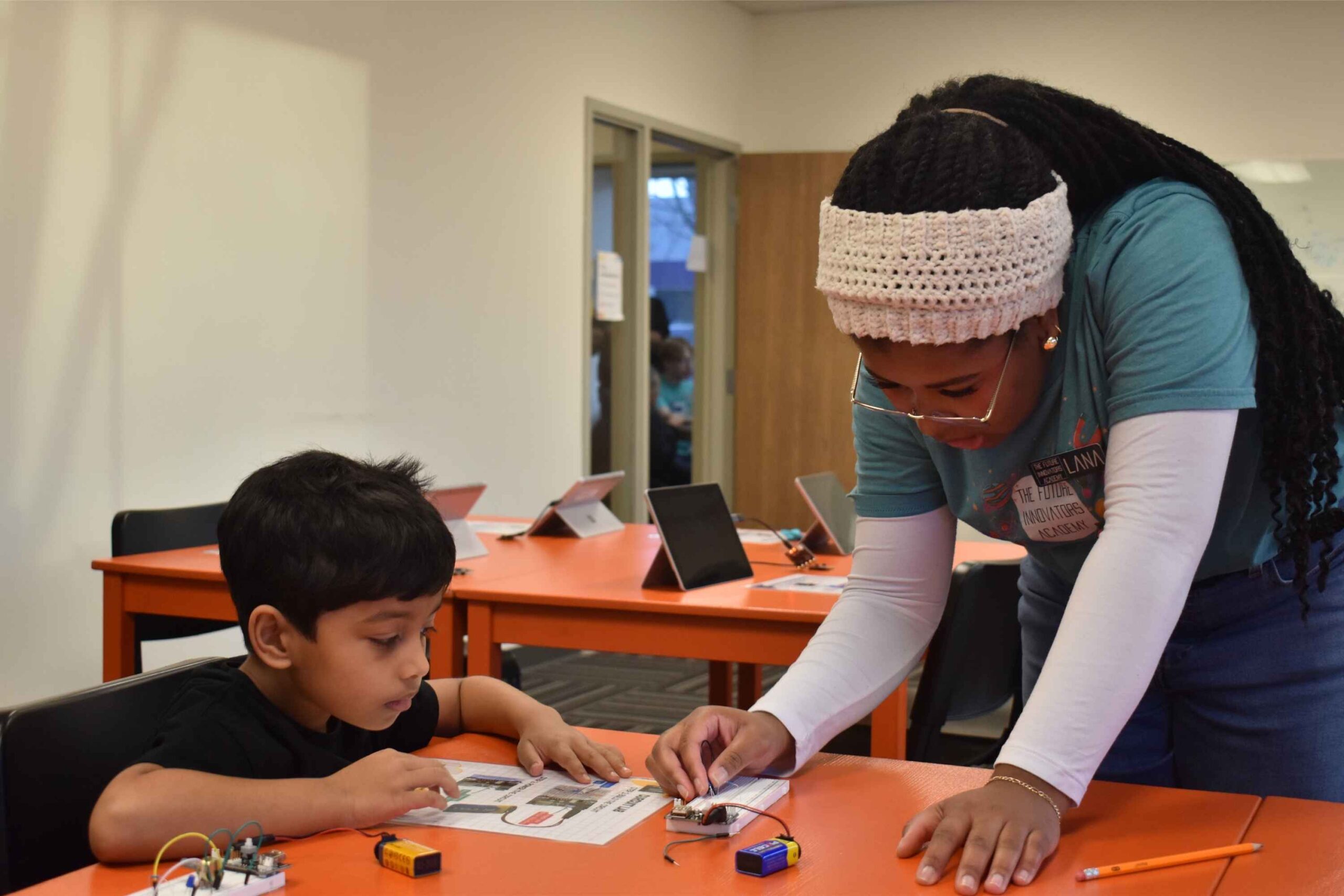 A STEM instructor helps a young camper build a hands-on electronics project at The Future Innovators Academy in Ann Arbor.