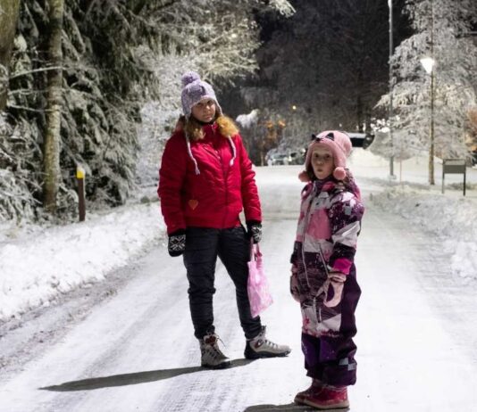 Family bundled up for Light the Night Flannel 5K walking a snowy trail at Waterford Oaks during the winter evening race