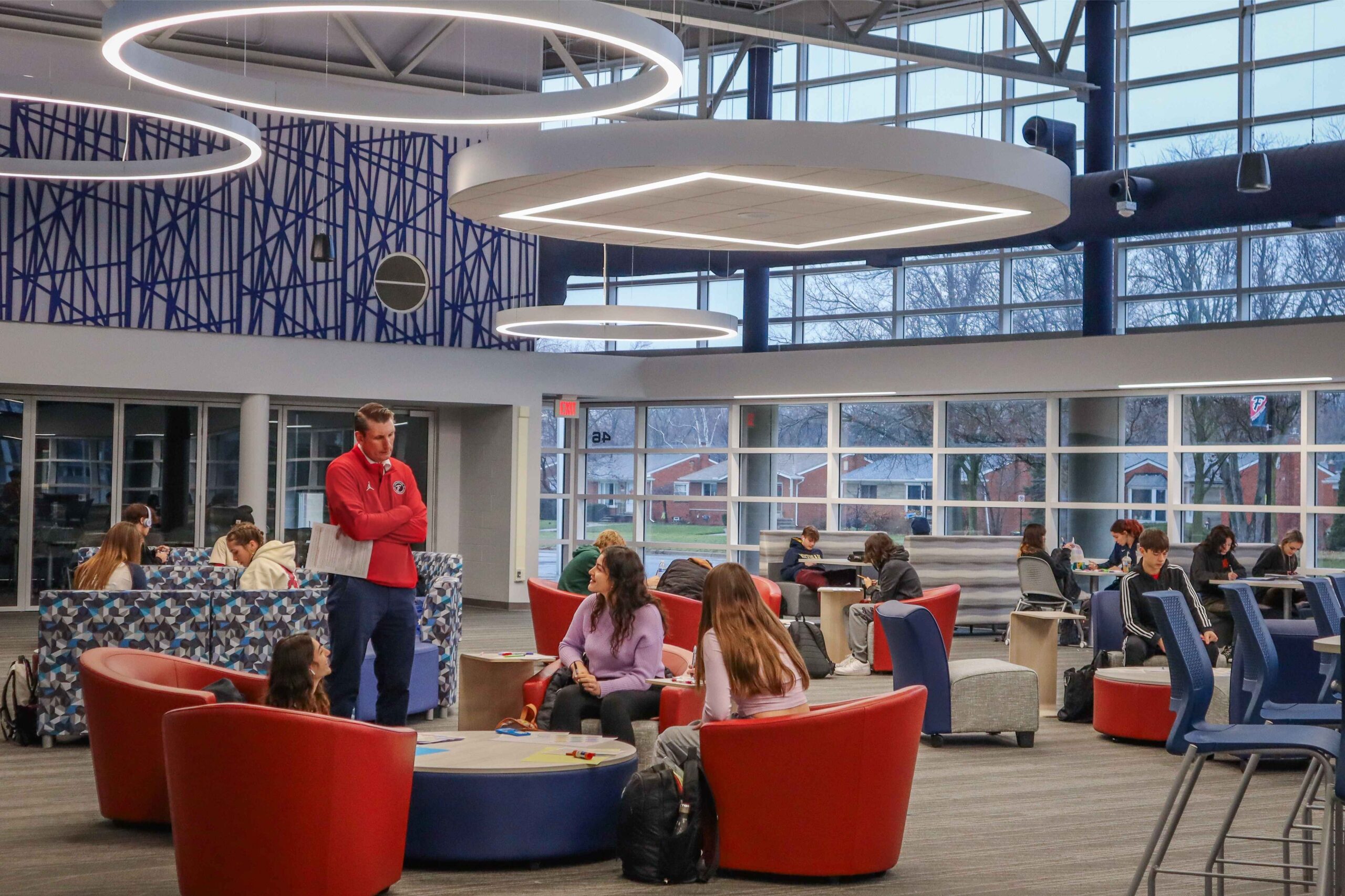 Students collaborating with a teacher in a modern common area at Livonia Public Schools, highlighting supportive learning spaces.