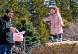 Child and parent enjoying Blake’s Backyard Almont Easter egg hunt during a family friendly spring farm event with hay bales and egg hunt fun