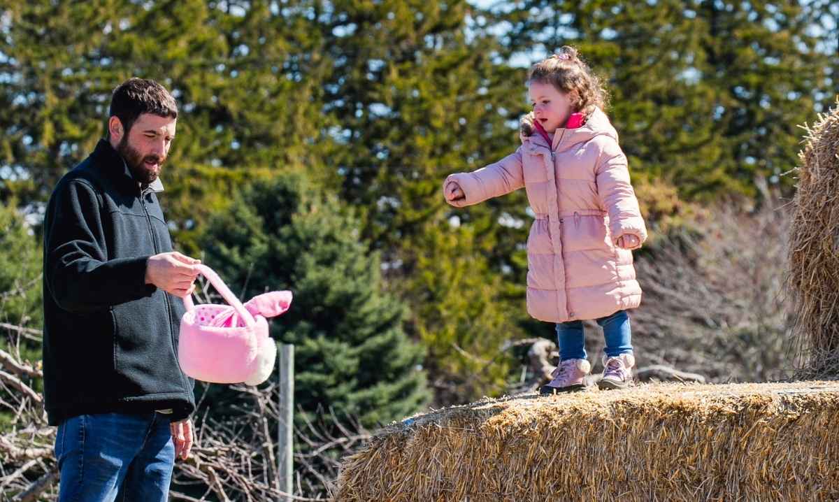 Child and parent enjoying Blake’s Backyard Almont Easter egg hunt during a family friendly spring farm event with hay bales and egg hunt fun