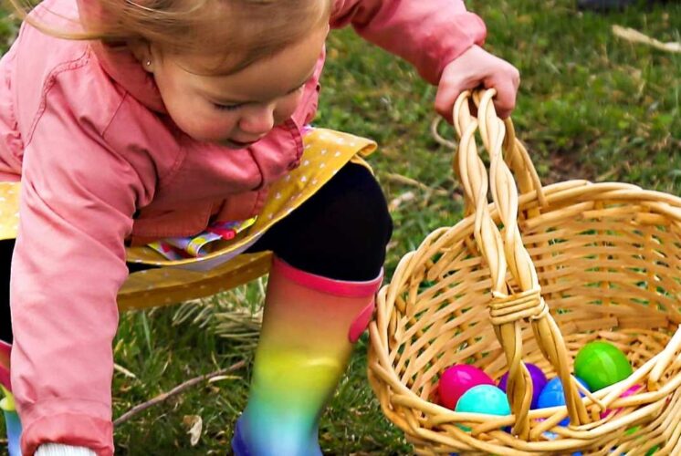 Child collecting colorful eggs during the Blake’s Lyon Twp Easter egg hunt with family friendly spring activities at the orchard
