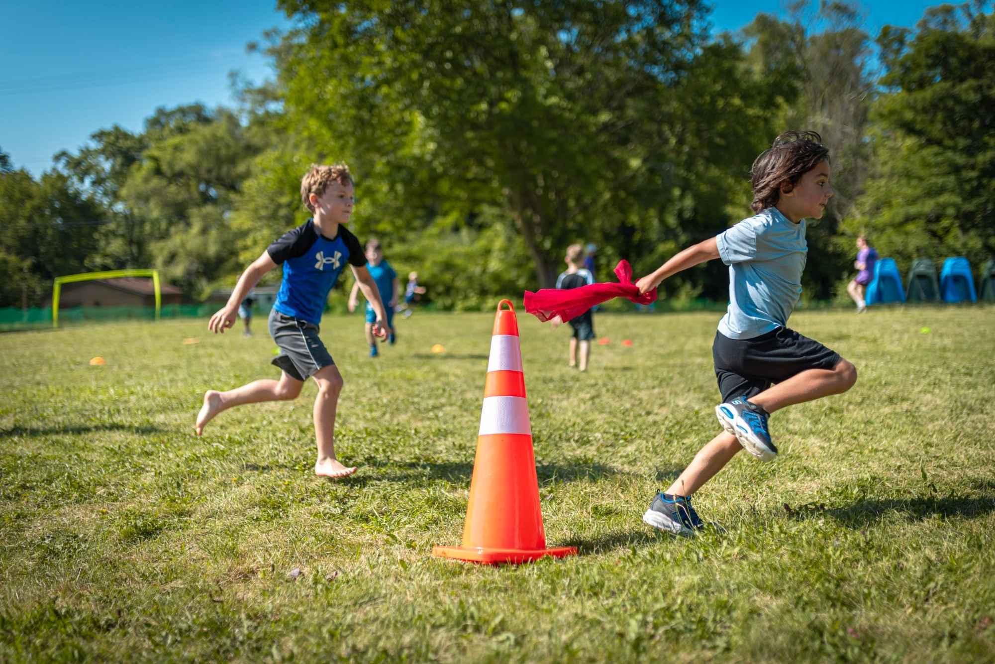 Kids play flag tag during outdoor field games at Camp Mirage summer camp in metro Detroit, enjoying active day camp fun and teamwork