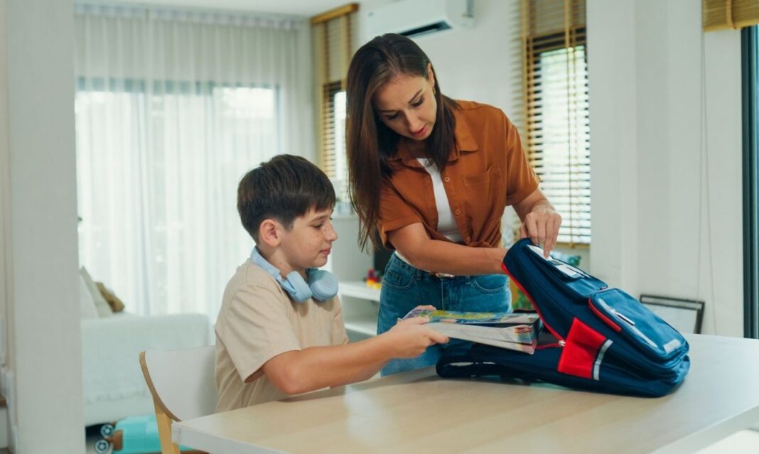 Parent helping child with autism pack backpack and get ready for school as part of morning routine