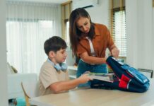 Parent helping child with autism pack backpack and get ready for school as part of morning routine
