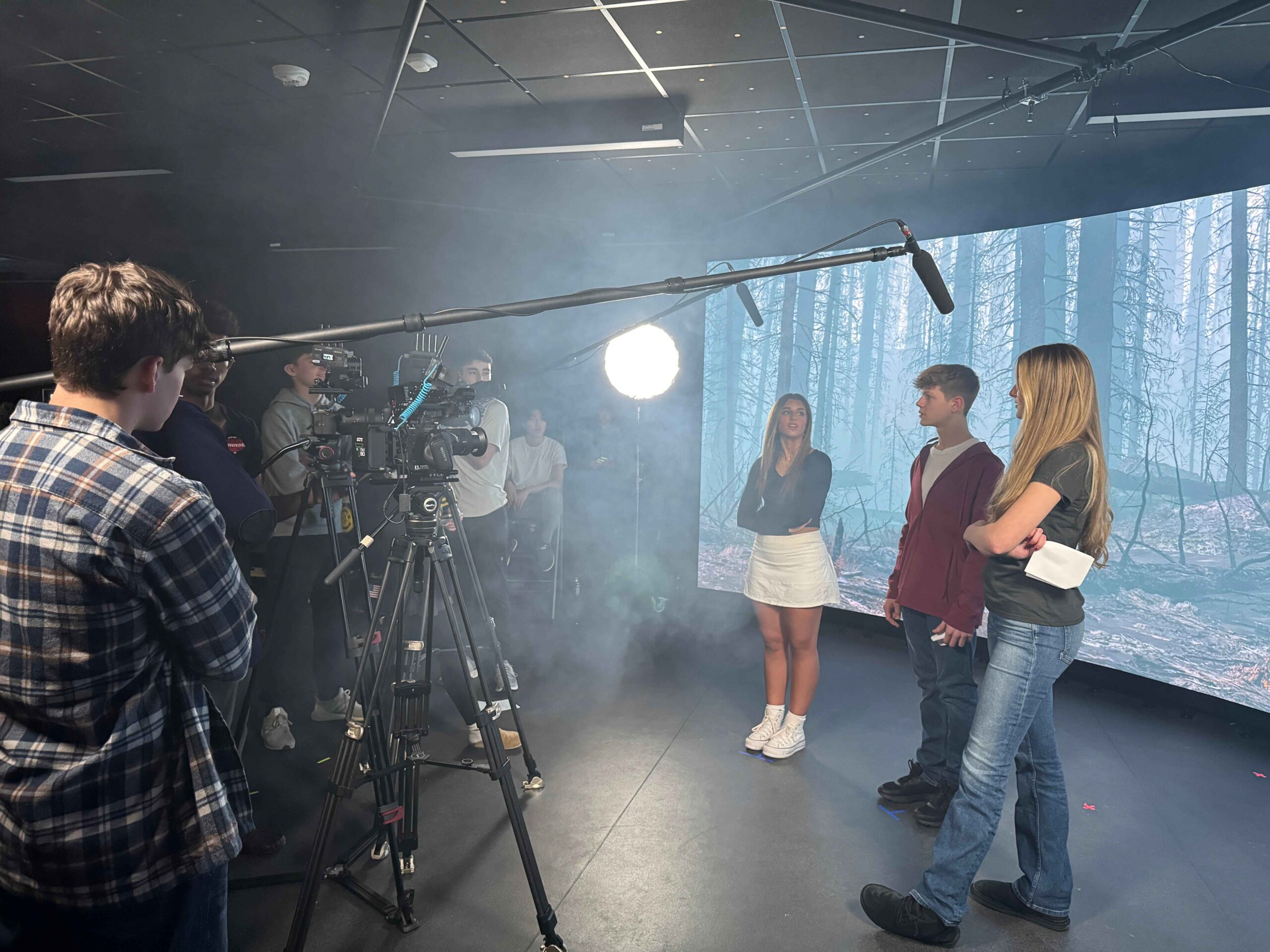Students film a scene in a filmmaking studio at Detroit Country Day Camps, using professional cameras, lighting and production equipment