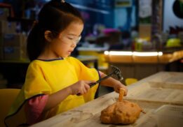 Child participates in hands-on archaeology craft during Family Day Children and Play in the Ancient World at the Kelsey Museum of Archaeology