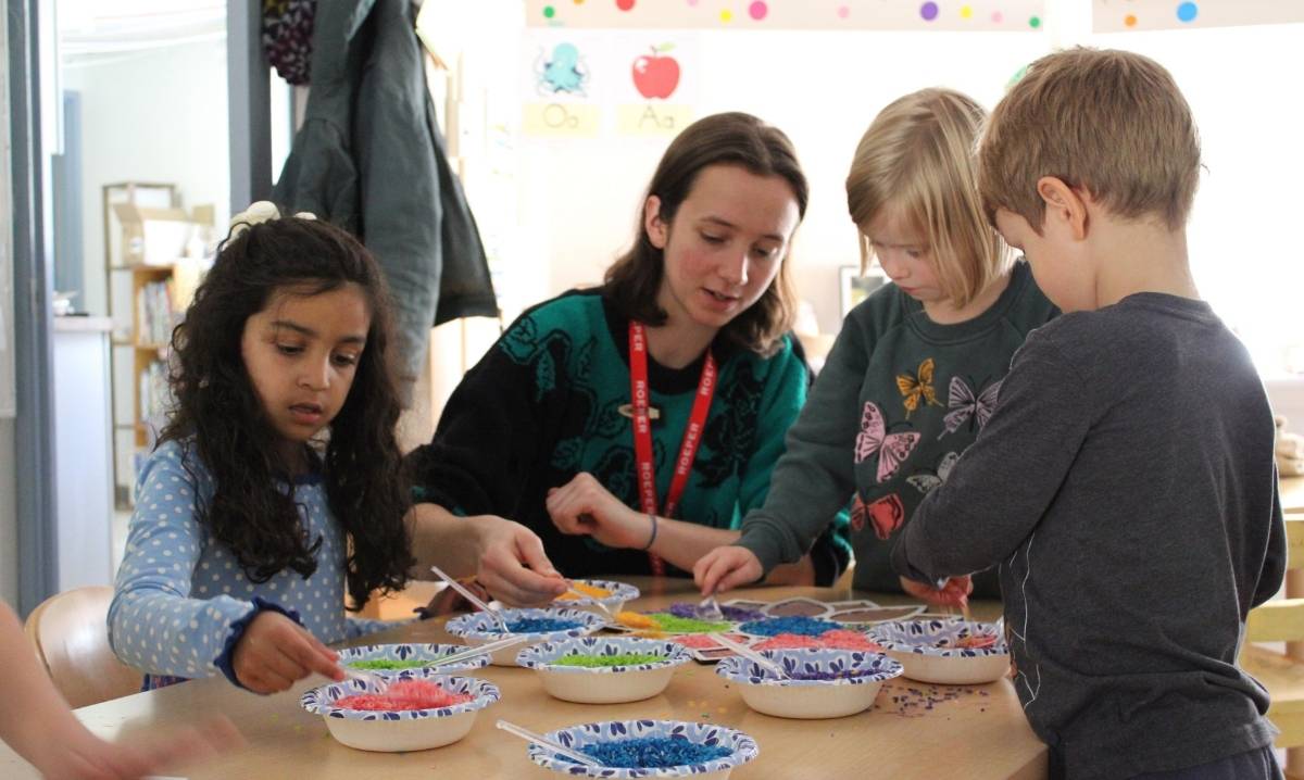 Kids work on arts and crafts with a teacher during spring break in Lansing, enjoying a hands on indoor learning activity for families