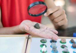 Child examines rock with magnifying glass during Science Saturdays at Briarwood Mall hands on STEM activity for kids and families