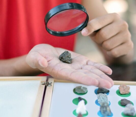 PreK Story & STEAM at Detroit Hives Nature Preserve Child examines rock with magnifying glass during Science Saturdays at Briarwood Mall hands on STEM activity for kids and families