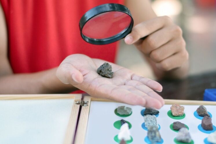 Child examines rock with magnifying glass during Science Saturdays at Briarwood Mall hands on STEM activity for kids and families