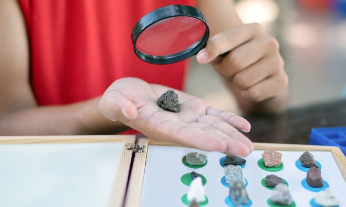 Child examines rock with magnifying glass during Science Saturdays at Briarwood Mall hands on STEM activity for kids and families