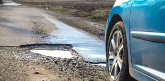 Southeast Michigan pothole survival scene with car tire approaching large pothole on winter road showing risks to tires suspension and alignment