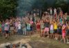 Campers gather around a campfire at YMCA Camp Torch Hayo-Went-Ha in Central Lake Michigan, building community through shared traditions and group activities