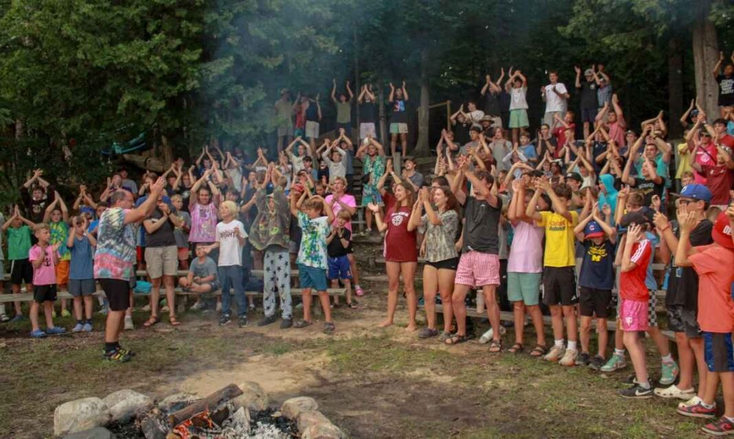 Campers gather around a campfire at YMCA Camp Torch Hayo-Went-Ha in Central Lake Michigan, building community through shared traditions and group activities