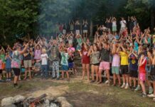 Where tradition meets the trail: YMCA Camp Torch Hayo-Went-Ha for Boys Campers gather around a campfire at YMCA Camp Torch Hayo-Went-Ha in Central Lake Michigan, building community through shared traditions and group activities