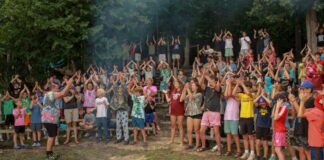 Campers gather around a campfire at YMCA Camp Torch Hayo-Went-Ha in Central Lake Michigan, building community through shared traditions and group activities