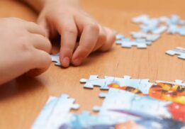Child working on a puzzle at a table during a family puzzle tournament event with kids focusing and building pieces together