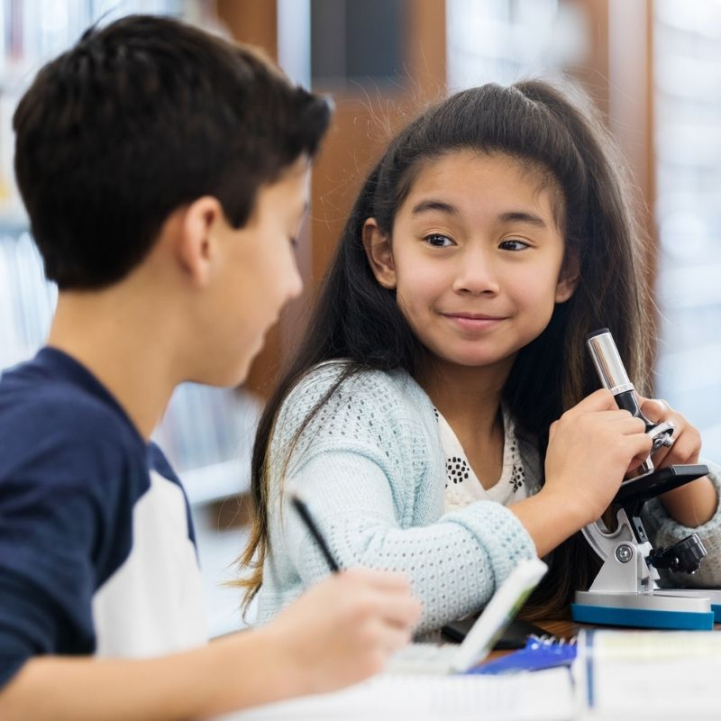 Elementary student smiling and holding an A graded test in a classroom, showing academic success and achievement