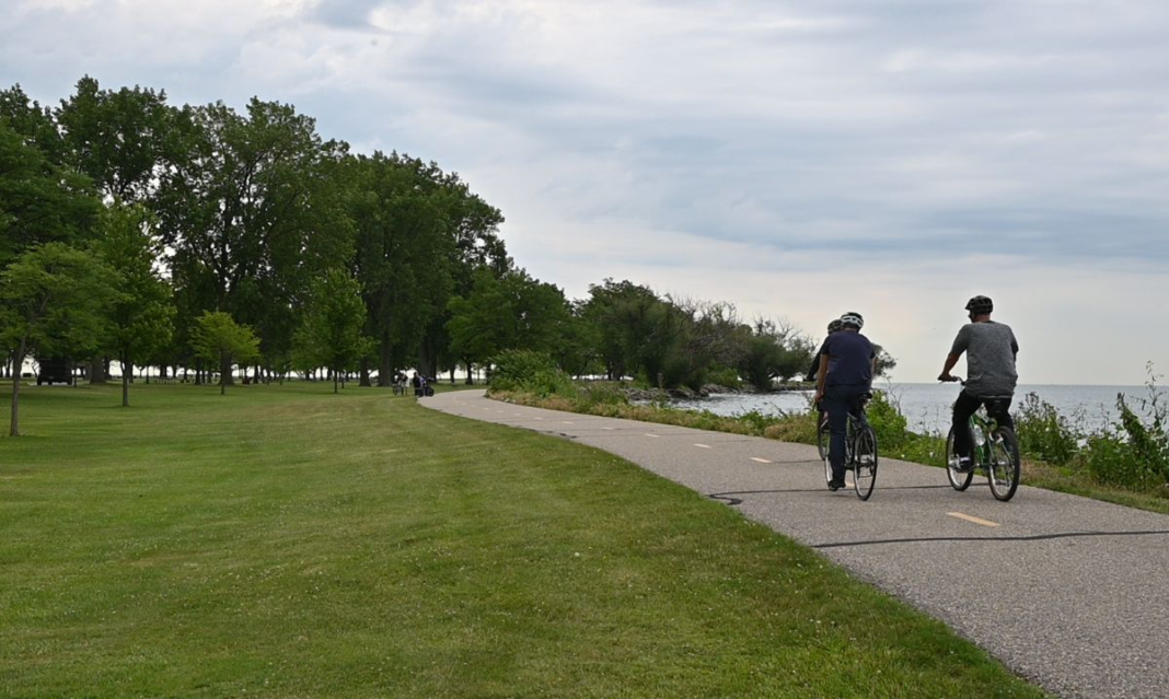 People riding bikes along a lakeside trail at a Macomb County metropark