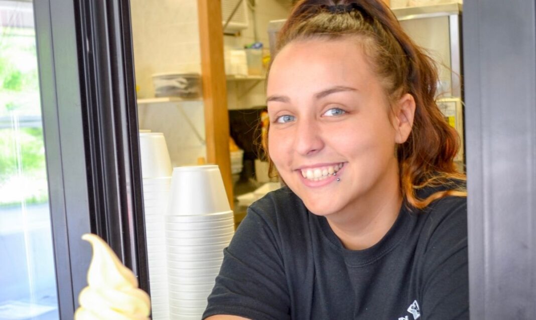 Smiling server at an ice cream stand in Muskegon serving sweet treats, highlighting family friendly restaurants and dessert spots